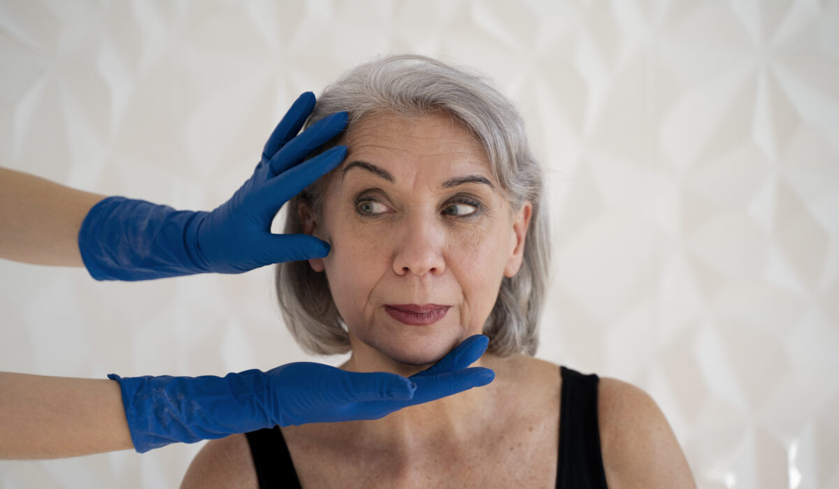visage de femme âgée tenue par des mains portant des gants bleue